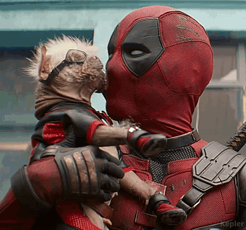 A Man In A Deadpool Costume Is Kissing A Small Dog GIF