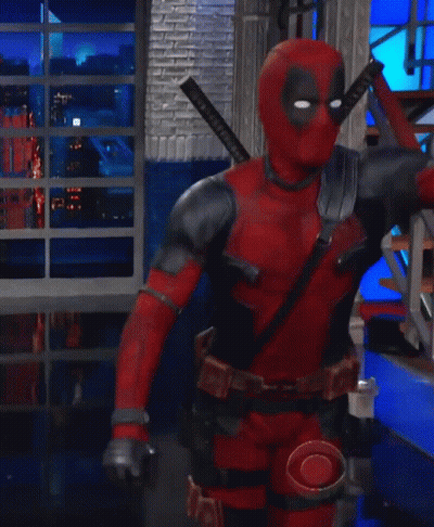A Man In A Deadpool Costume Is Kneeling Down In A Room With Stairs GIF