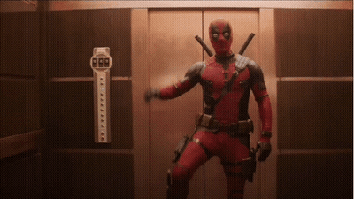 A Man In A Deadpool Costume Is Standing In An Elevator Holding A Gun . GIF