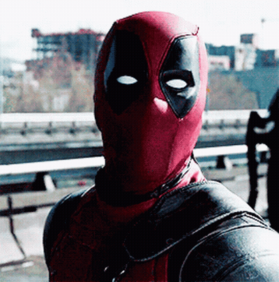 A Man In A Deadpool Costume Is Standing In Front Of A Bridge GIF
