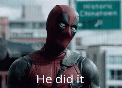 A Man In A Deadpool Costume Is Standing In Front Of A Green Sign . GIF