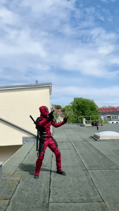 A Man In A Deadpool Costume Is Standing On A Rooftop GIF