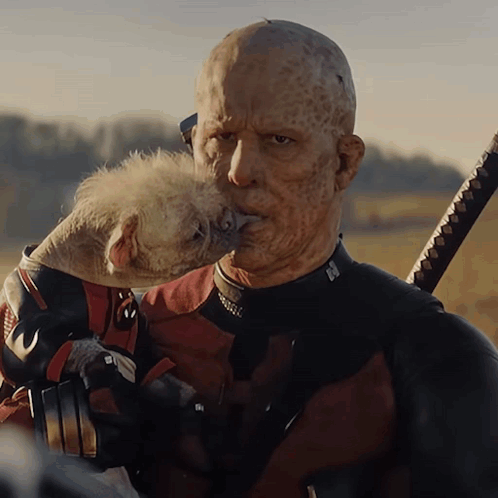 A Man In A Deadpool Suit Holds A Dog GIF