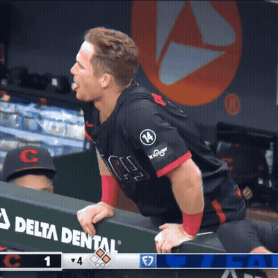 A Man In A Delta Dental Jersey Leans Over A Dugout Wall GIF