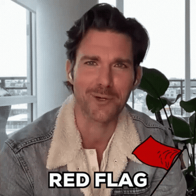 A Man In A Denim Jacket Is Holding A Red Flag With The Word Red Flag Written On It GIF