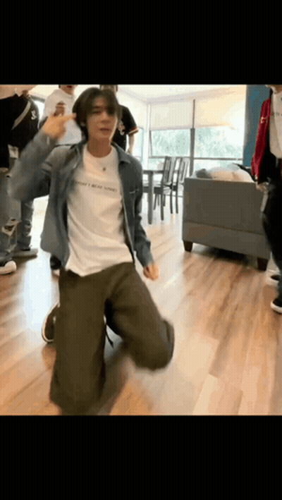 A Man In A Denim Jacket Is Kneeling Down And Dancing In A Room . GIF