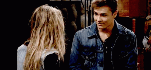 A Man In A Denim Jacket Is Looking At A Woman GIF