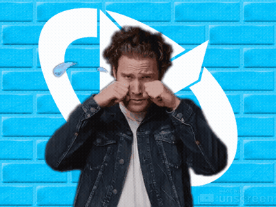 A Man In A Denim Jacket Is Rubbing His Nose In Front Of A Blue Brick Wall Made By Unscreen GIF
