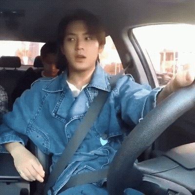 A Man In A Denim Jacket Is Sitting In A Car With A Seat Belt On . GIF