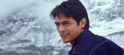 A Man In A Denim Jacket Is Smiling And Looking At The Camera . GIF