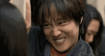 A Man In A Denim Jacket Is Smiling And Making A Funny Face In A Crowd Of People . GIF
