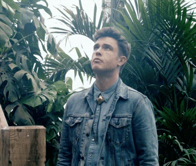 A Man In A Denim Jacket Is Standing In A Jungle GIF