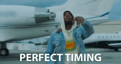 A Man In A Denim Jacket Is Standing In Front Of An Airplane With The Words Perfect Timing Written On The Bottom GIF