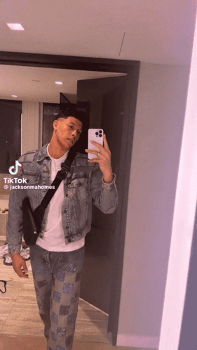 A Man In A Denim Jacket Is Taking A Picture Of Himself In A Mirror .. GIF