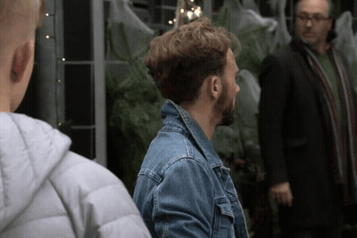 A Man In A Denim Jacket Stands Next To Another Man In A Suit GIF