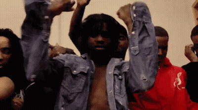 A Man In A Denim Shirt Is Dancing With His Arms In The Air . GIF
