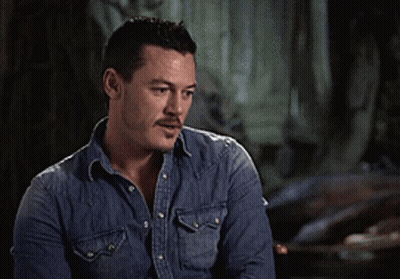 A Man In A Denim Shirt Is Making A Peace Sign With His Hands GIF