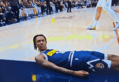 A Man In A Denver Nuggets Uniform Lays On The Floor GIF