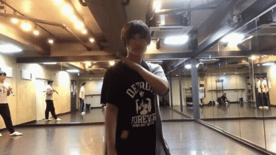 A Man In A Detroit Forever Shirt Is Standing In Front Of A Mirror GIF