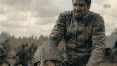A Man In A Dirty Jacket Is Holding Another Man 'S Helmet With The Hbo Logo On The Bottom GIF