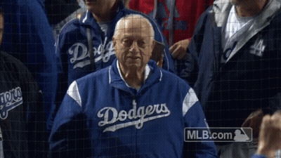 A Man In A Dodgers Jacket Stands In The Crowd GIF