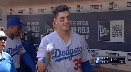 A Man In A Dodgers Jersey Holds A Baseball In A Dugout GIF