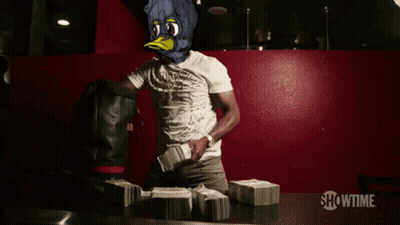 A Man In A Duck Mask Stands In Front Of Stacks Of Money With Showtime Written On The Bottom GIF