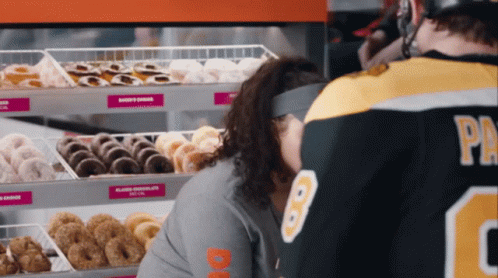 A Man In A Dunkin Donuts Jersey Looks At A Woman 'S Face GIF