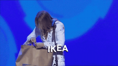 A Man In A Elvis Costume Is Holding A Bag With The Word Ikea On It GIF