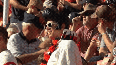 A Man In A Elvis Presley Costume Stands In A Crowd GIF