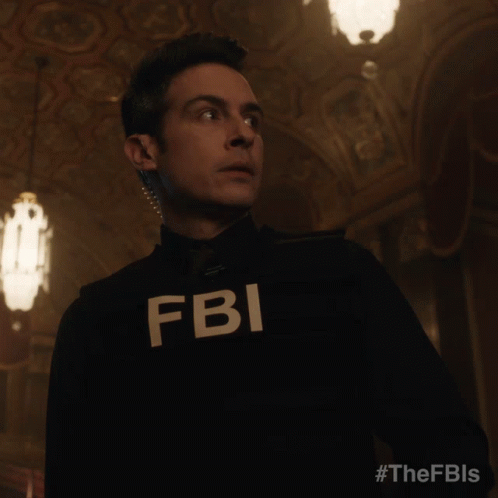 A Man In A Fbi Uniform Stands In A Dark Hallway GIF