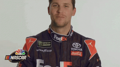 A Man In A Fedex Racing Suit Is Standing In Front Of A Nascar Logo . GIF