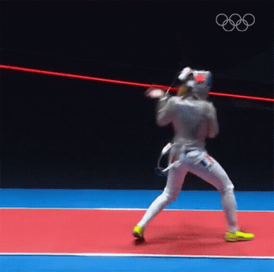 A Man In A Fencing Uniform Is Standing On A Red And Blue Court . GIF