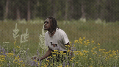 A Man In A Field Of Flowers Wearing A Boy Shirt GIF