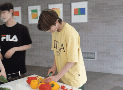 A Man In A Fila Shirt Is Cutting Peppers GIF