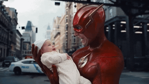 A Man In A Flash Costume Holds A Baby GIF