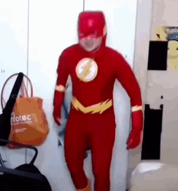 A Man In A Flash Costume Is Standing In Front Of A Door . GIF