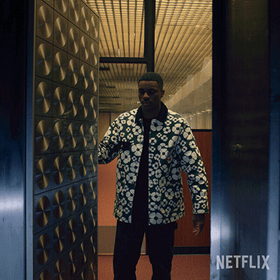A Man In A Floral Jacket Is Standing In A Doorway With A Netflix Logo On The Bottom GIF