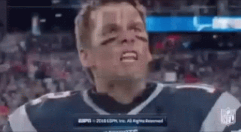 A Man In A Football Jersey Is Making A Funny Face While Standing In Front Of A Crowd . GIF