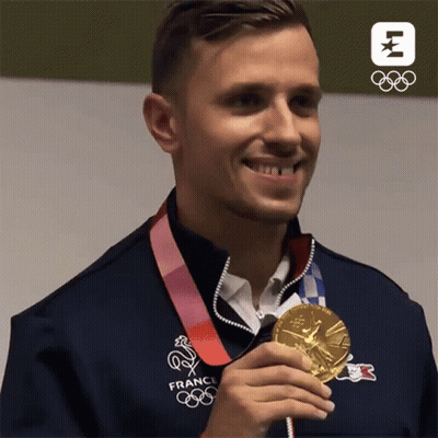 A Man In A France Olympics Jacket Holds A Gold Medal GIF
