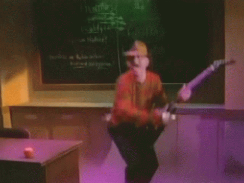 A Man In A Freddy Krueger Costume Is Playing A Guitar In Front Of A Blackboard GIF