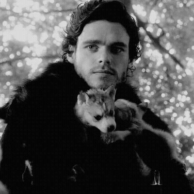 A Man In A Fur Coat Is Holding A Small Dog In His Arms GIF