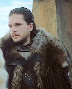 A Man In A Fur Coat Is Standing In Front Of A Stone Building GIF