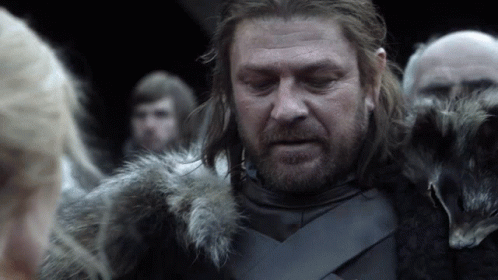 A Man In A Fur Coat Stands In Front Of A Group Of People GIF