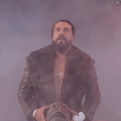 A Man In A Fur Coat With Studded Sleeves Is Holding A Crown GIF
