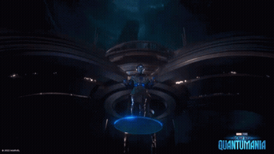A Man In A Futuristic Suit Is Standing In A Dark Room With A Blue Circle Around Him . GIF