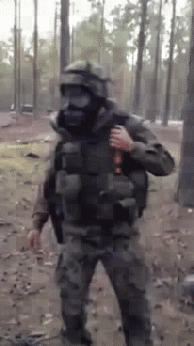 A Man In A Gas Mask Is Holding A Bottle In His Hand GIF