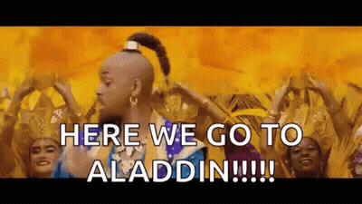 A Man In A Genie Costume Is Standing In Front Of A Group Of Women Dancing . GIF