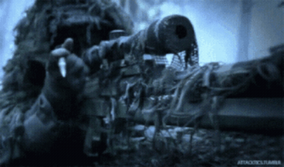 A Man In A Ghillie Suit Is Holding A Sniper Rifle In His Hand GIF