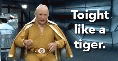 A Man In A Gold Costume Is Sitting In A Chair With The Words Tonight Like A Tiger Behind Him . GIF